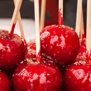 Homemade, caramel-coated candy apples on a platter, ready to be enjoyed, with a glossy, colorful coating that tempts the taste buds.